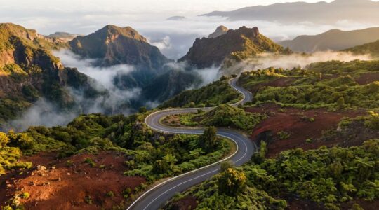 Route sinueuse traversant les paysages volcaniques des Hauts de La Réunion avec végétation tropicale et remparts
